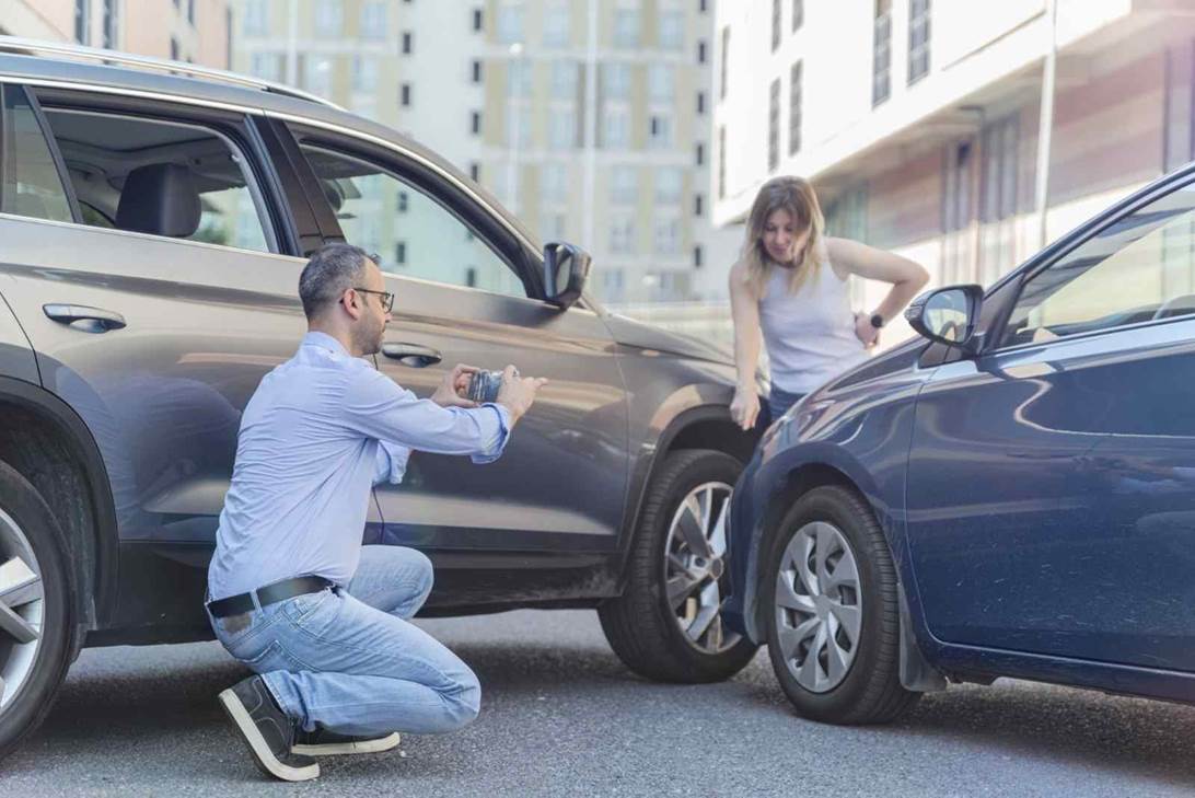 A person kneeling on the ground next to a car with a person in the background

AI-generated content may be incorrect.